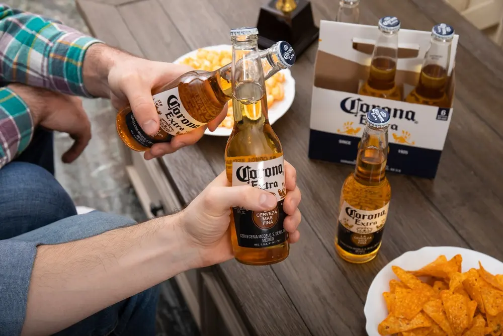 Two people holding Corona beer bottles with chips for snacks in Floyd, VA