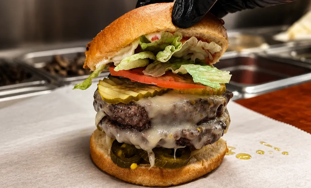 Fresh double-patty deli burger with tomato, lettuce, cheese, and pickles at Floyd Xpress Market in Floyd, VA